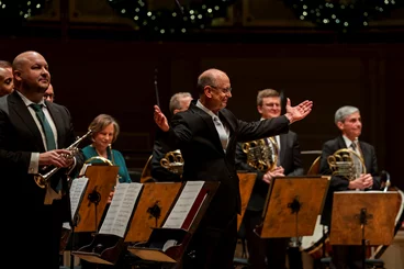 conductor Michael Mulcahy gestures for the ensemble to take a bow